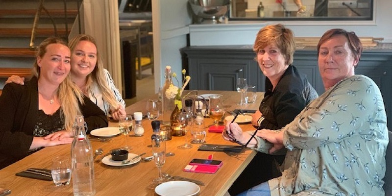 four women sitting at a table drinking wine and water