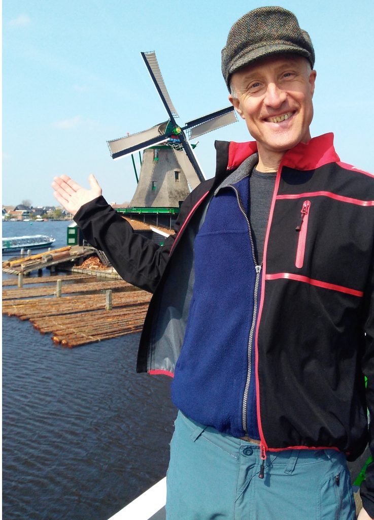 Ein Mann zeigt auf die Windmühle von Zaanse Schans.