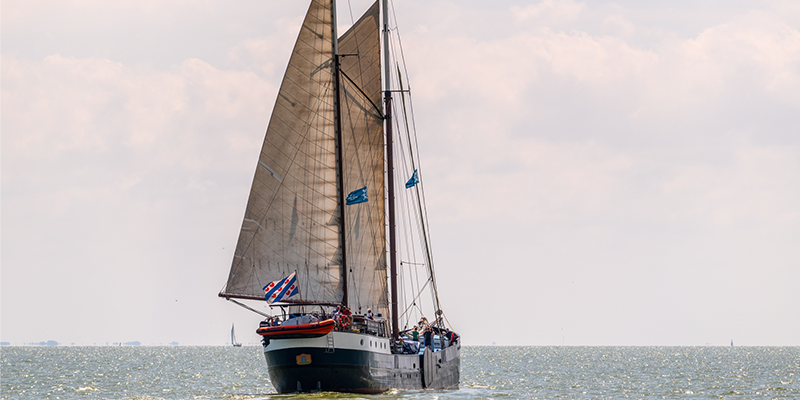 A sailing ship with hoisted sail at sea.